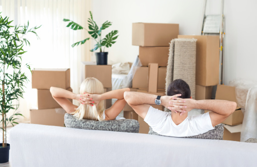 Couple relaxing on a sofa surrounded by packed boxes, symbolizing the stress-free experience of using Big Tex Storage for their moving and storage needs in Houston, TX.